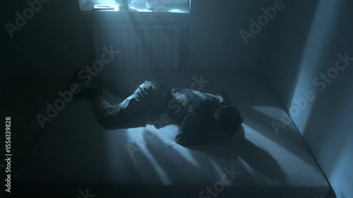 Man in despair, dealing with loss of money, love, and job in moody blue room. Male hitting mattress