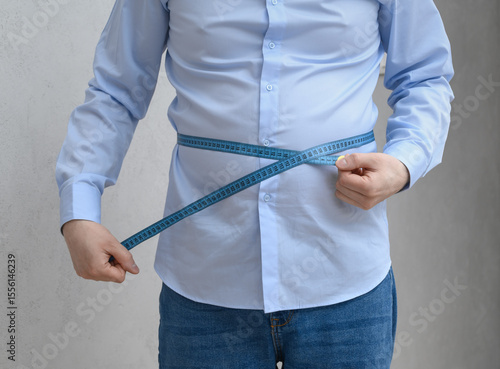 Ταπετσαρία An overweight man measures the circumference of his protruding, swollen belly