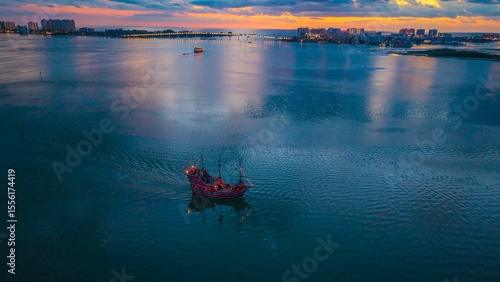 A lone pirate ship returns to port after a beautiful Florida sunset.  The lighted Sand Key bridge is shown in the background.