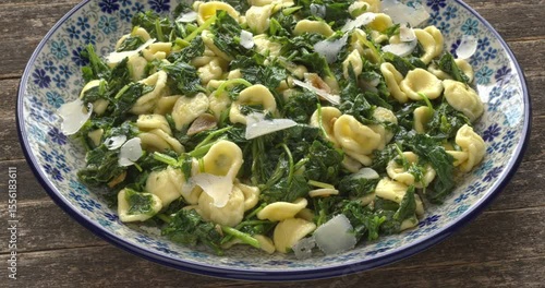 Orecchiette pasta with broccoli rabe (rapini) on a plate. South Italian dish. Rapini is a rich source of vitamin K.  Table spin. 