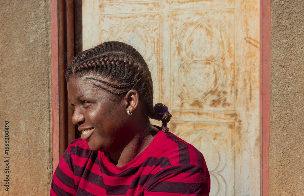Naklejka premium Africa village, african woman girl with braids dreadlocks , in front of the house