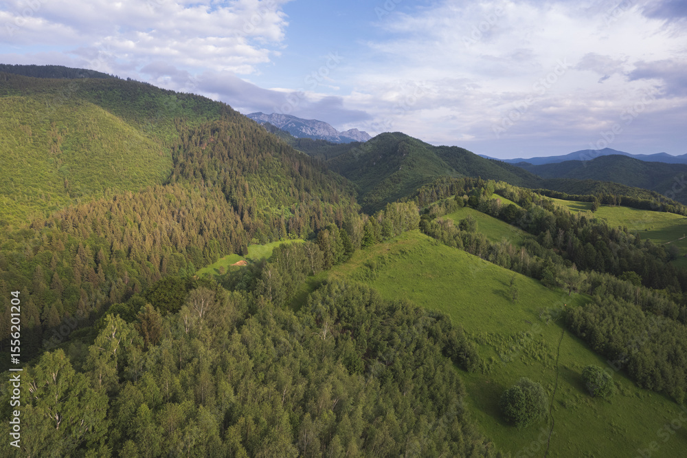 Obraz premium Aerial view of the Transylvanian hills at sunset – rural landscape with green forests and traditional cottages at the mountain edge 