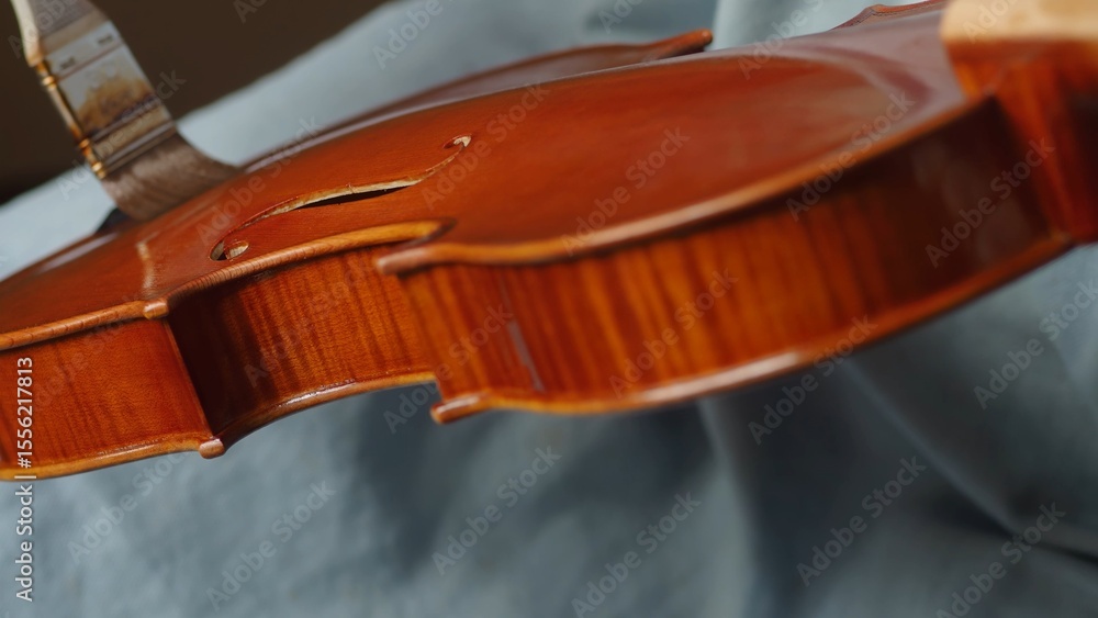 Obraz premium Skilled craftsman applying protective varnish to violin body, highlighting intricate woodworking techniques in musical instrument creation