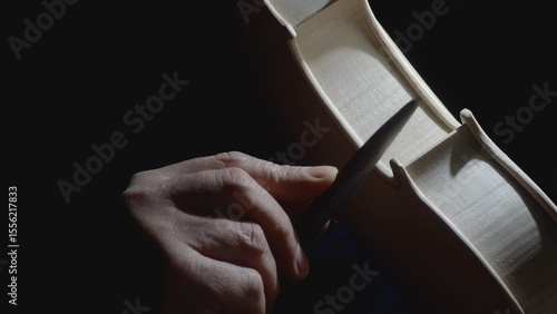 Fotografie Skilled craftsman carefully filing intricate details of wooden violin body, high