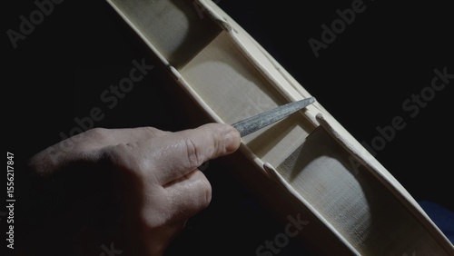 Obraz na plátně Skilled craftsman carefully filing intricate details of wooden violin body, high