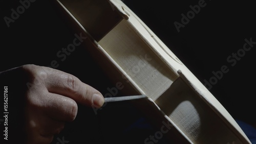 Obraz na plátně Skilled craftsman carefully filing intricate details of wooden violin body, high