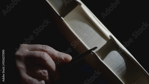 Obraz na plátně Skilled craftsman carefully filing intricate details of wooden violin body, high