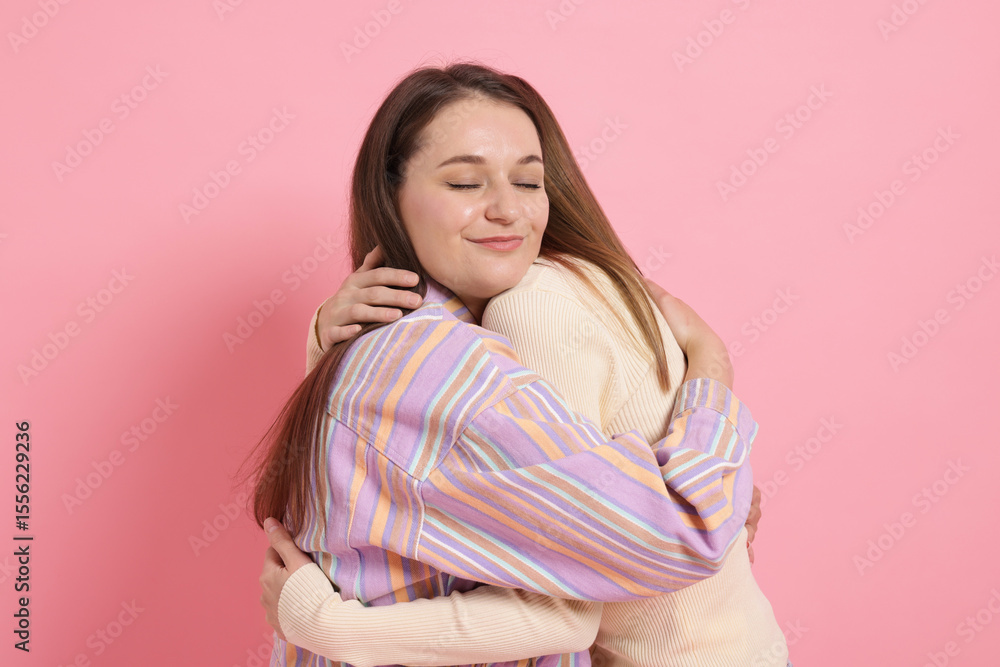 Obraz premium Two happy friends hugging on pink background