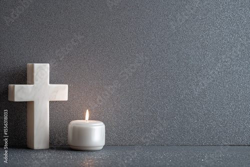 White Cross on the wall and a white candle on Dark grey background 