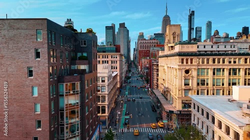 Following multiple yellow cabs in the traffic by the Fifth Avenue. Drone footage along the facades of the buildings in New York City.