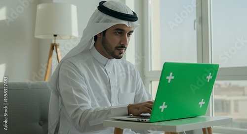 Arab Man Works From Home, Focused on His Green Laptop