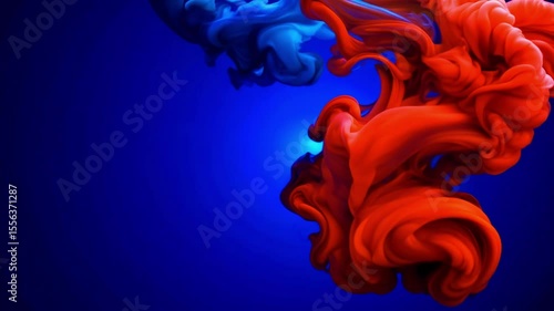 Red paint dramatically flows and swirls through deep blue water creating mesmerizing abstract liquid patterns with dynamic color contrast and fluid motion for artistic design