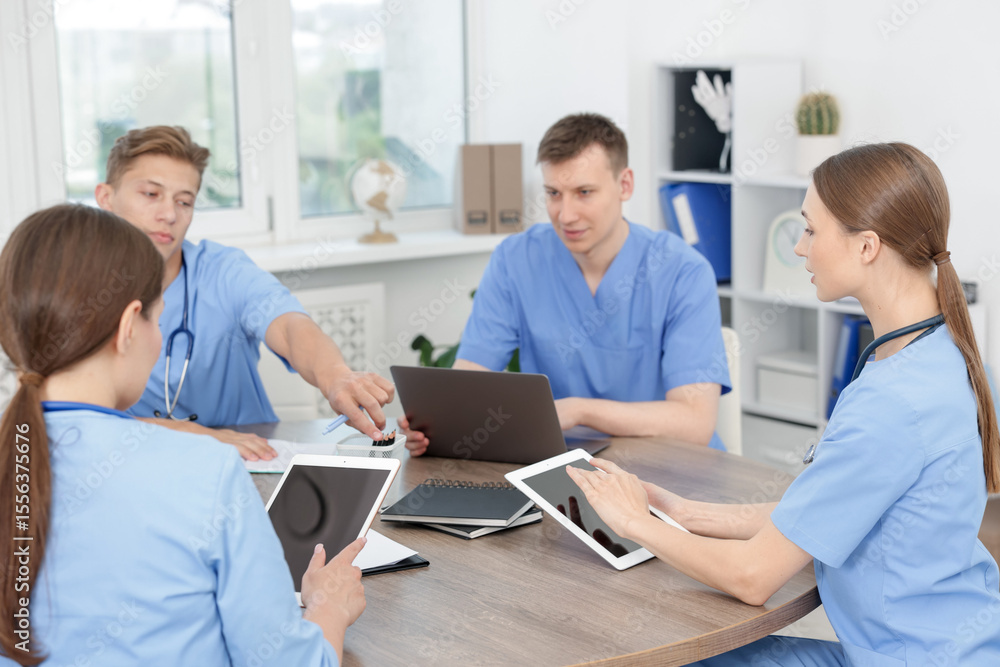 Obraz premium Medical students in uniforms studying together at table indoors