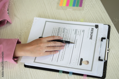 A young asian female Head of HR is reading resume and making a call for the recruitment interview process with the candidate who has been selected to work in the company, employment and HR concept.
