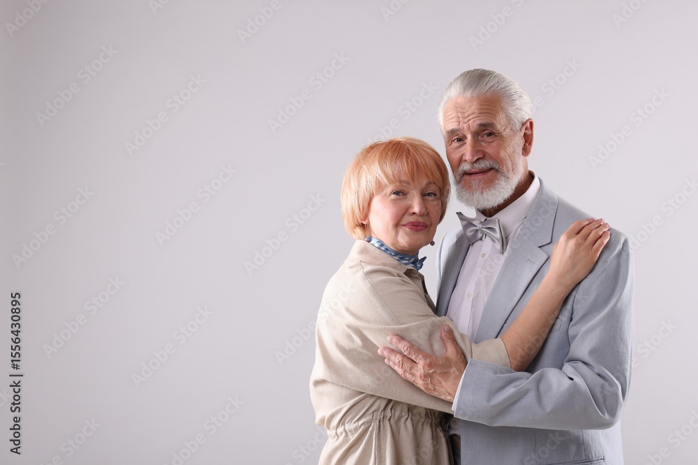 Lovely senior couple together on light grey background, space for text Lovely senior couple together on light grey background, space for text