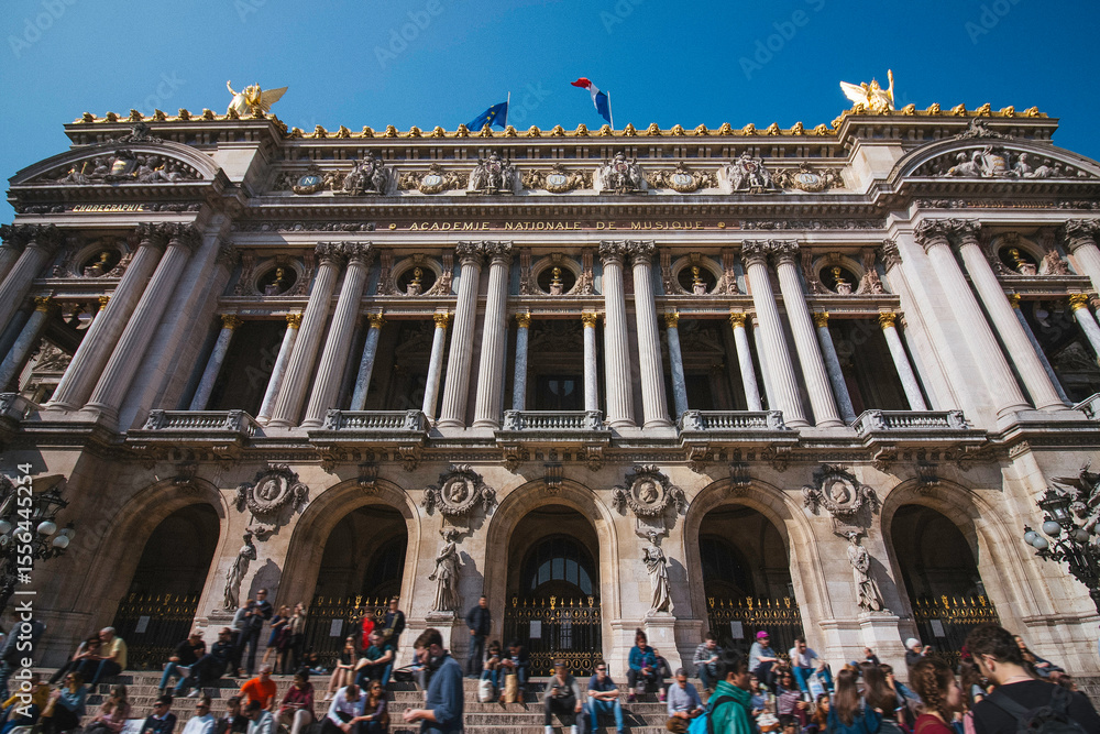 Fototapeta premium Crowd Enjoying The Sunny Weather Sitting On The Stairs Of The Opera Garnier In Paris, France