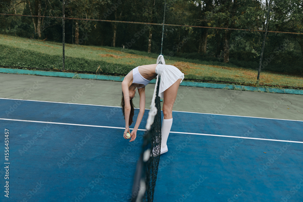 © SHOTPRIME STUDIO - Young athletic woman stretching on a tennis court in a sporty outfit, showcasing a dedication to fitness and a healthy lifestyle