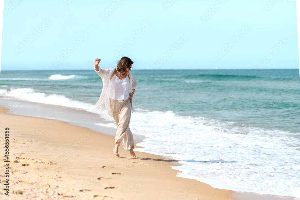 Beautiful mature woman having fun running away from the waves on sandy beach on sunny summer day. Beautiful mature woman having fun running away from the waves on sandy beach on sunny summer day.
