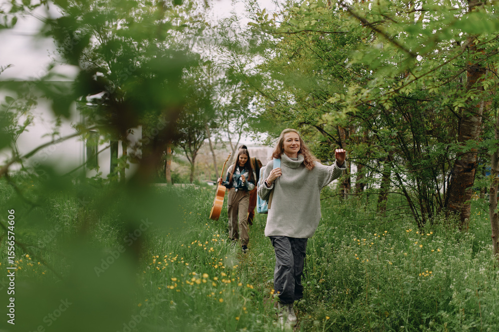 Fototapeta premium Middle age woman enjoying active outdoor walk with friends in lush green park, embracing wellness, health, and community lifestyle in spring season.