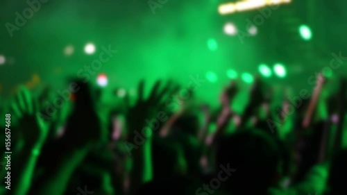 Bokeh view of people dancing on the dance floor during a concert at a festival. Blurred background footage. Concept of crowd enjoying rock and roll, live dj set, hip hop rap party, night club event.