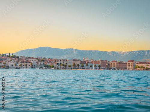 Sunset over Split, Croatia, with historic waterfront buildings and distant mountains reflected in the Adriatic Sea—an idyllic Mediterranean cityscape full of charm and color.