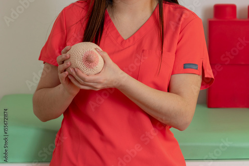 Pediatrician holding knitted breast model in pediatric office