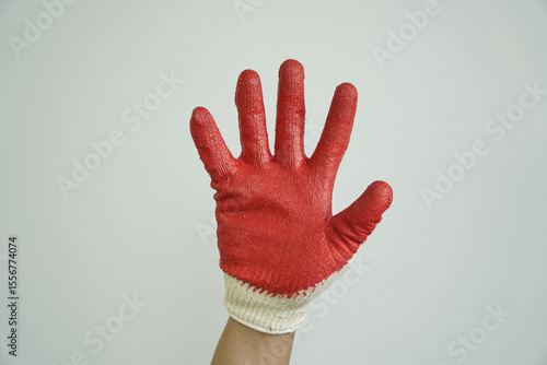 Hand in a red and white work glove held up with palm facing forward, signaling stop, warning, or refusal.