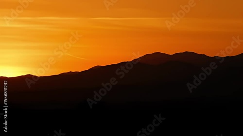Wallpaper Mural Mountains silhouetted against a bright orange and yellow sunset sky Torontodigital.ca