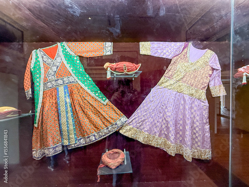 Two dresses are displayed in a glass case, one of which is purple