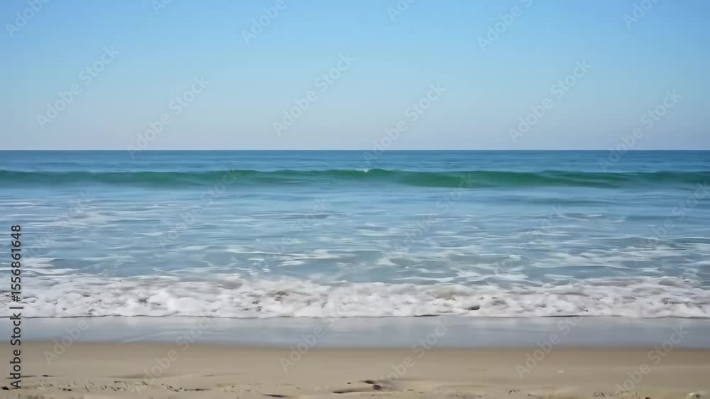 Calm ocean waves gently breaking on a sandy beach under a clear blue sky Calm ocean waves gently breaking on a sandy beach under a clear blue sky