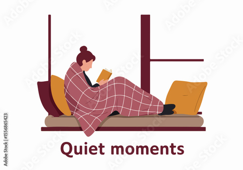 Woman wrapped in a blanket reading a book on a window seat, enjoying a quiet and cozy moment indoors.