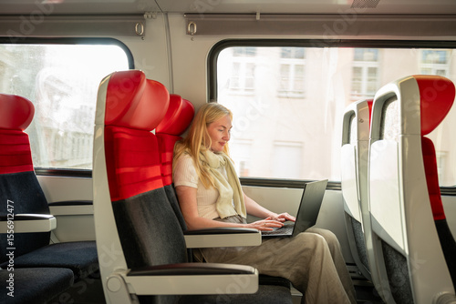 Canvas Print Woman working on laptop while traveling by train in bright daylight