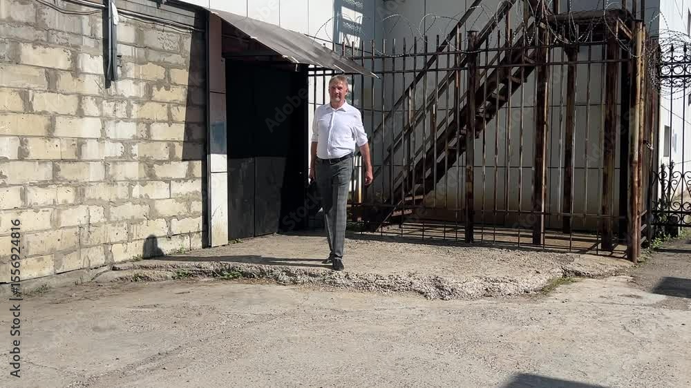 A man casually walks through an open gate, enjoying the peaceful atmosphere of the private area. A man casually walks through an open gate, enjoying the peaceful atmosphere of the private area.