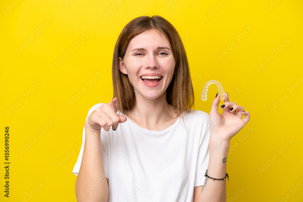 Young English woman holding invisible braces surprised and pointing front Young English woman holding invisible braces surprised and pointing front