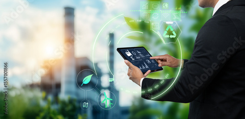 Sustainable Technology for Industry Smart Solutions for Environmental Management concept, business man using digital tablet on blurred green industry as background
