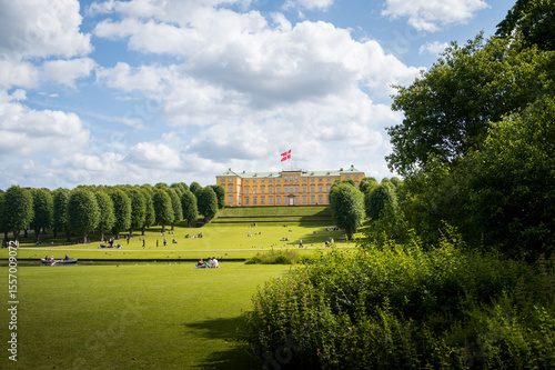 People relaxing on the lawn in front of Frederiksberg Palace in Copenhagen Denmark on warm summer day