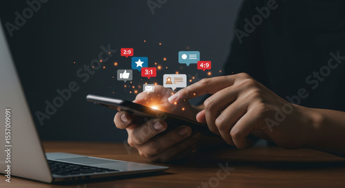 Person Typing on Mobile Device with Social Media Notifications Hologram and Laptop on Wooden Table Against Dark Background