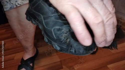 Woman cleaning spring boots for cold weather with brush in evening. Home shoe care concept