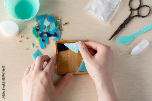 Faux stained glass fragments positioned in silicone mold to make handmade mosaic-style coaster with plaster powder and tools for home decor DIY project, step 1