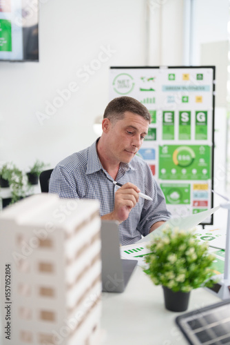 Adult Caucasian man analyzes ESG report for sustainable business growth carbon footprint reduction planning renewable energy solutions and future development