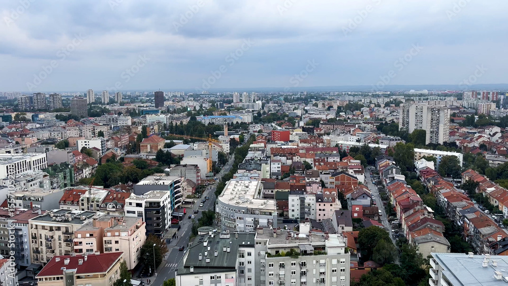Fototapeta premium Top view of a large European city. Red-tiled roofs and high-rise buildings are visible. Drogues between houses. Life in a big city.