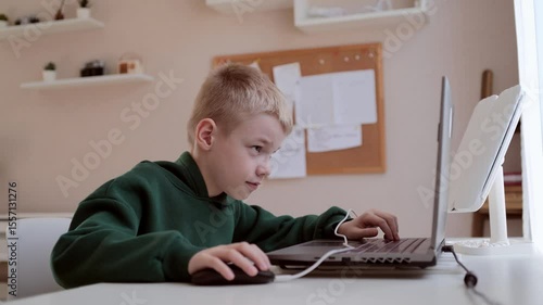 A boy with hearing aids engages with a laptop and tablet, showcasing modern childhood's digital learning and inclusive tech play. Perfect for education and disability awareness content