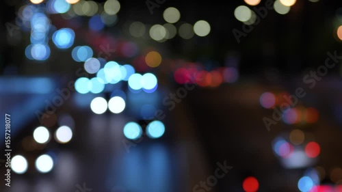 Defocused city traffic lights at night creating colorful bokeh effect. Abstract urban motion background with blurred headlights and taillights, perfect for overlays, transitions, and cinematic scenes
