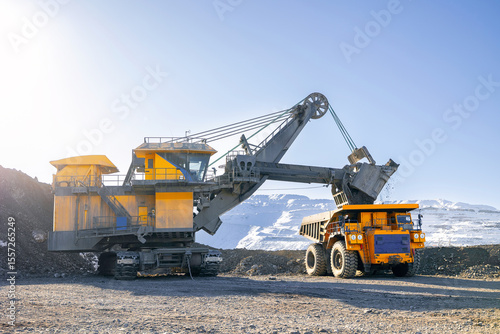 Photos Banner Open-pit coal mining in winter, heavy machinery excavator loading dump tr