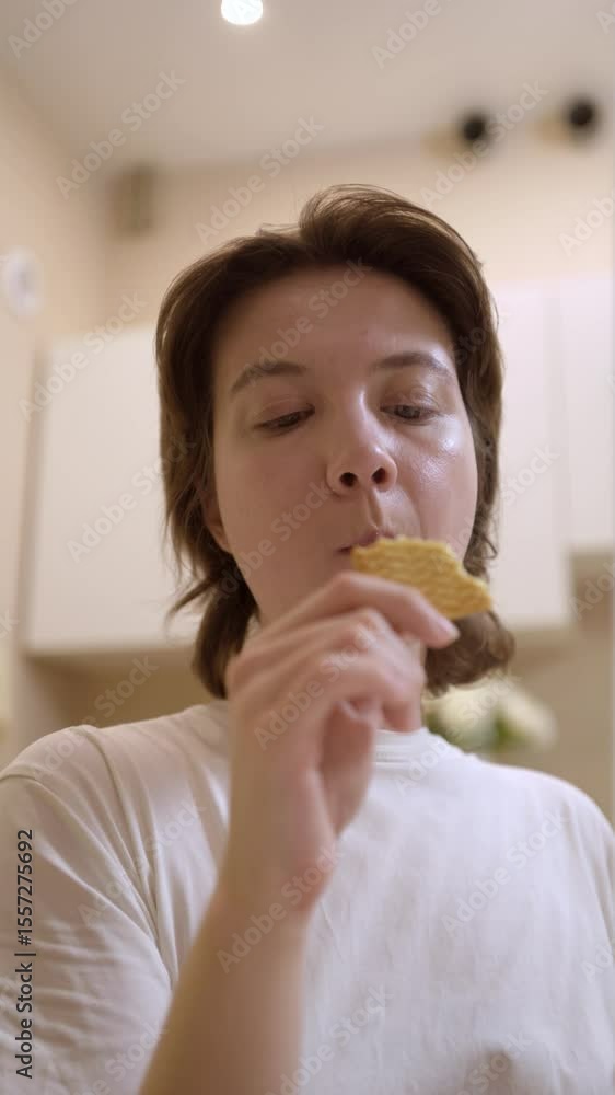 A young woman enjoys a simple meal and drinks tea in her cozy kitchen. Authentic, unposed moment capturing real emotions and the warmth of everyday life. Perfect for lifestyle and food content A young woman enjoys a simple meal and drinks tea in her cozy kitchen. Authentic, unposed moment capturing real emotions and the warmth of everyday life. Perfect for lifestyle and food content