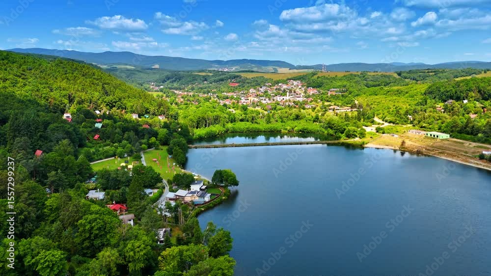 Lakefront European village. A picturesque view captures a charming village nestled by a serene lake, framed by lush trees and mountains. Lakefront European village. A picturesque view captures a charming village nestled by a serene lake, framed by lush trees and mountains.