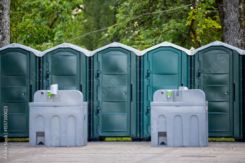 portable outdoor toilets with handwashing stations in public park area mobile sanitation units for events hygiene facilities restroom cabins portable washbasins in green nature environment setup