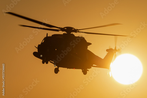 A helicopter is flying during a beautiful sunset. 