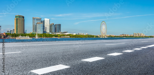 Quadro su tela Empty asphalt road and modern city skyline with lakeside amusement park scenery in Suzhou, China