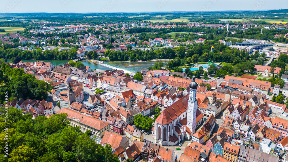 Fototapeta premium Landsberg am Lech, charming Bavarian town captured from drone. Historic old town, Lech River, Mariä Himmelfahrt Church, aquapark, small waterfall and colorful summer scenery